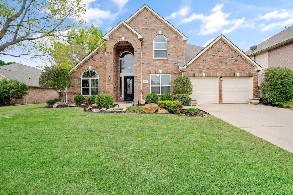 traditional home with brick siding, a garage, a front lawn, and driveway