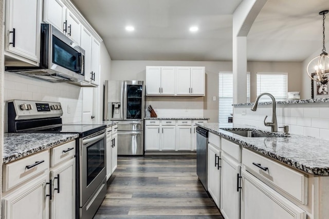 kitchen featuring dark wood finished floors, recessed lighting, decorative backsplash, appliances with stainless steel finishes, and a sink