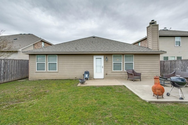 back of property featuring a lawn, roof with shingles, a patio area, and a fenced backyard