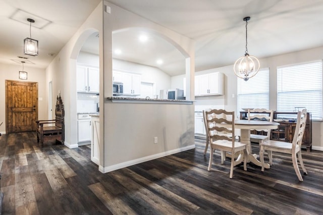 dining area with arched walkways, a notable chandelier, baseboards, and dark wood-type flooring