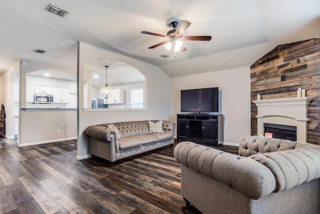 living room with dark wood-style flooring, visible vents, a ceiling fan, and vaulted ceiling