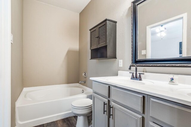 full bathroom with toilet, a bathtub, wood finished floors, and vanity