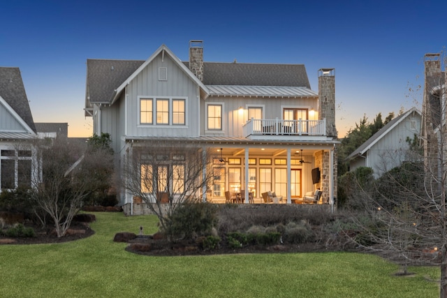 13270 Waterside Dr, Malakoff, TX 75148 - back of property at dusk with a chimney, a balcony, a lawn, board and batten siding, and a ceiling fan