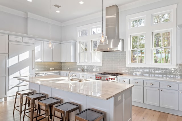 13270 Waterside Dr, Malakoff, TX 75148 - kitchen featuring wall chimney range hood, a sink, a breakfast bar area, crown molding, and white cabinets