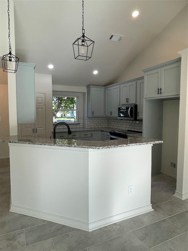 240 Wells St, Emory, TX 75440 - kitchen featuring stainless steel microwave, light stone countertops, decorative backsplash, decorative light fixtures, and lofted ceiling