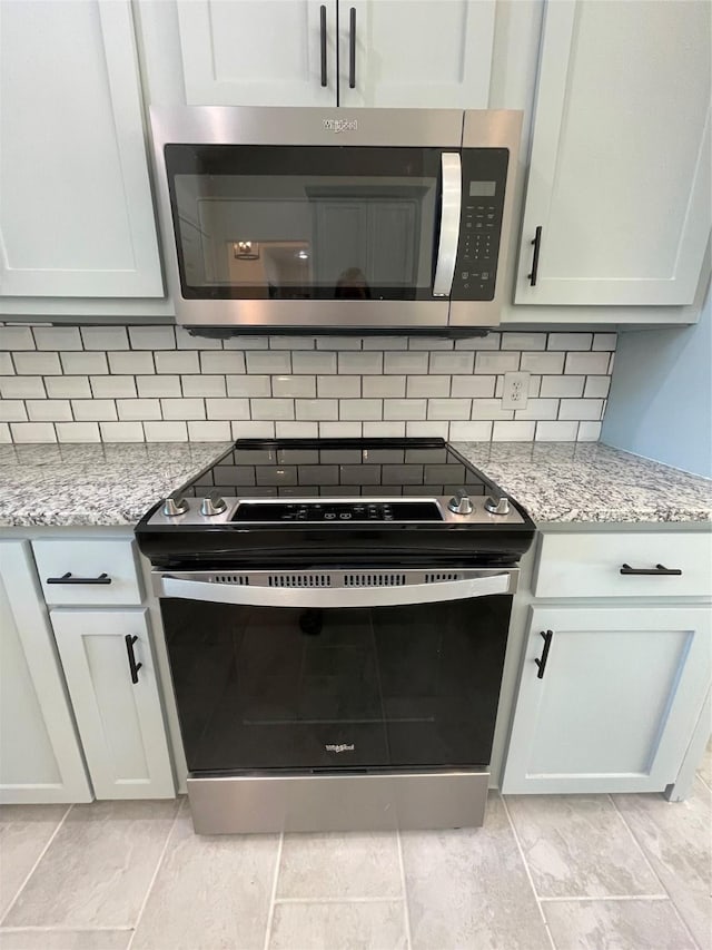 240 Wells St, Emory, TX 75440 - kitchen view of appliances with stainless steel finishes, backsplash, light stone counters, and white cabinets