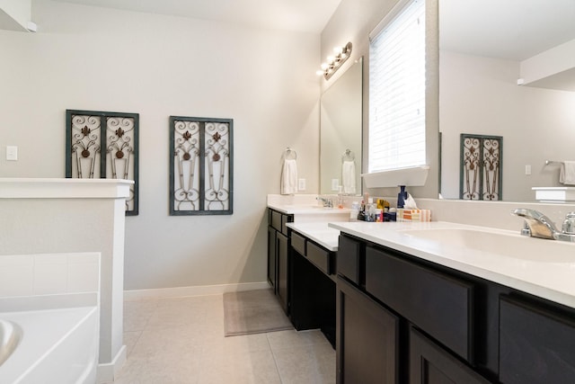 bathroom with double vanity, a garden tub, tile patterned flooring, a sink, and baseboards