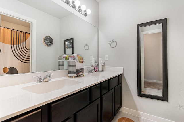 full bathroom with baseboards, a sink, and double vanity