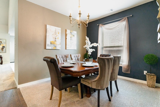 dining space with visible vents, baseboards, light wood finished floors, an inviting chandelier, and light carpet