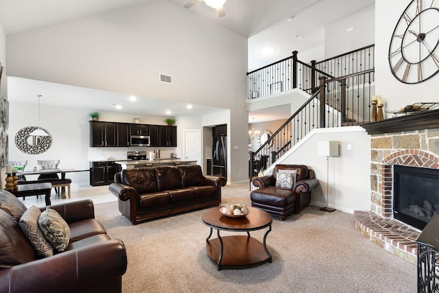 living area featuring visible vents, a stone fireplace, high vaulted ceiling, and light colored carpet