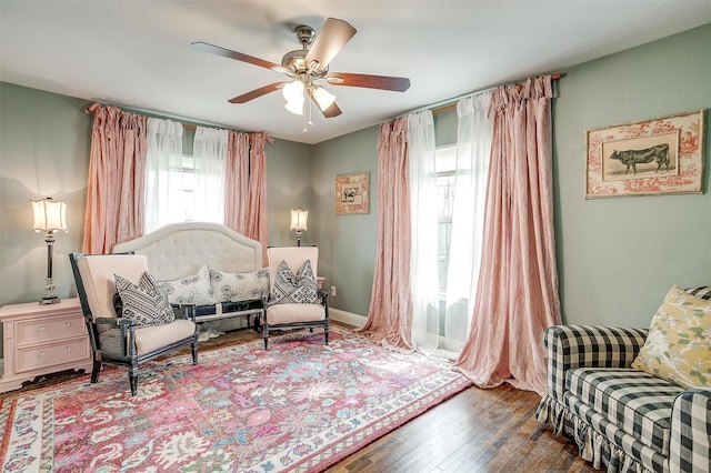 sitting room with baseboards, ceiling fan, and wood finished floors