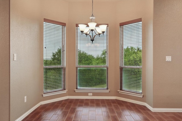 unfurnished dining area with baseboards, dark wood-style flooring, and a notable chandelier