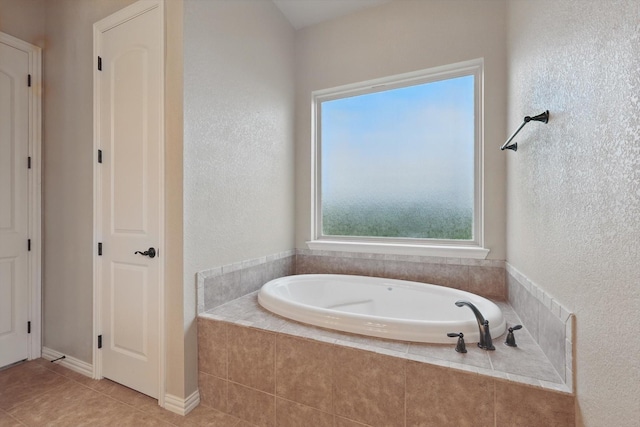 bathroom with tile patterned flooring, a textured wall, and a bath