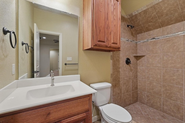 full bathroom featuring visible vents, vanity, toilet, a textured wall, and tiled shower