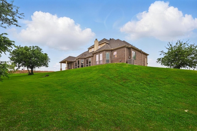 back of property with a chimney, a yard, and brick siding