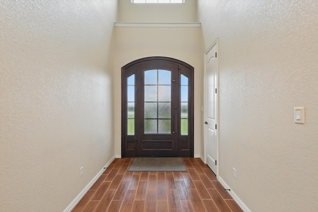 entrance foyer featuring a healthy amount of sunlight, arched walkways, baseboards, and dark wood-style floors