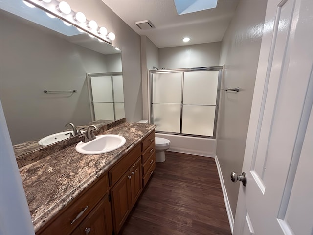 3308 Omega Dr, Tyler, TX 75701 - full bathroom featuring vanity, wood finished floors, and bath / shower combo with glass door