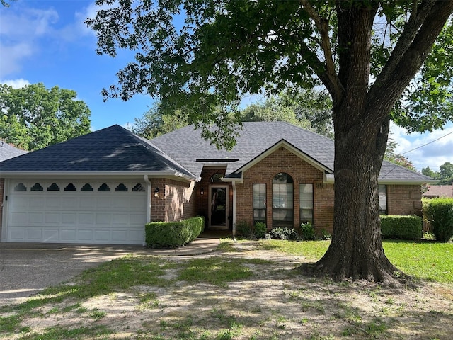 3308 Omega Dr, Tyler, TX 75701 - view of front of home with brick siding, a shingled roof, driveway, and an attached garage