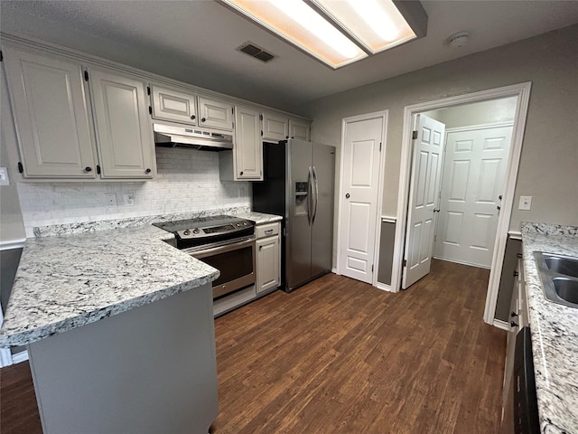 3308 Omega Dr, Tyler, TX 75701 - kitchen featuring appliances with stainless steel finishes, under cabinet range hood, backsplash, dark wood-style flooring, and a peninsula