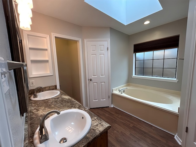 3308 Omega Dr, Tyler, TX 75701 - full bathroom with a skylight, a garden tub, wood finished floors, double vanity, and built in shelves