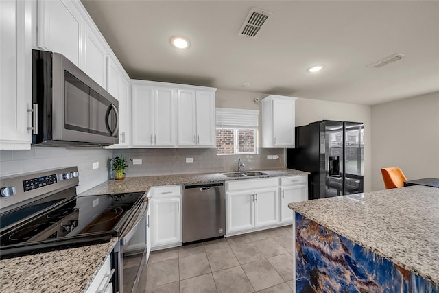 1718 Ackerly Dr, Forney, TX 75126 - kitchen with appliances with stainless steel finishes, a sink, white cabinets, decorative backsplash, and light tile patterned floors