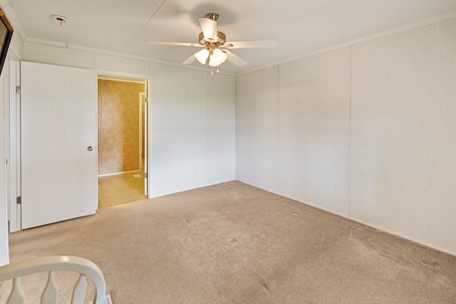 carpeted empty room featuring ceiling fan and crown molding