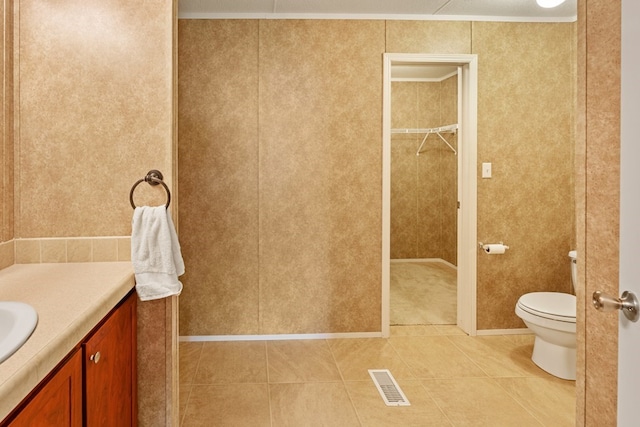 bathroom featuring tile patterned floors, a walk in closet, vanity, toilet, and visible vents
