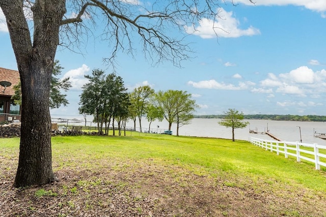 view of yard with fence, a boat dock, and a water view