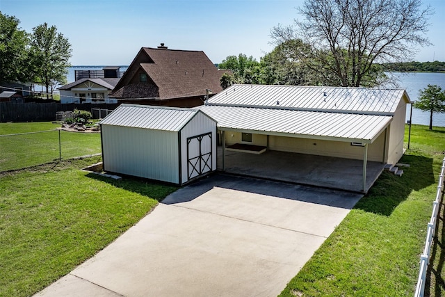 exterior space with concrete driveway, fence, a storage unit, and metal roof