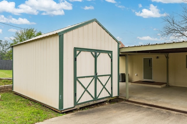 view of shed with a carport, fence, and central air condition unit