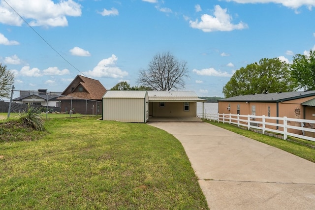 rear view of property featuring a lawn, driveway, and fence