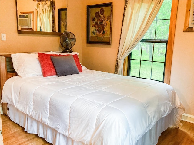 bedroom with wood finished floors and an AC wall unit