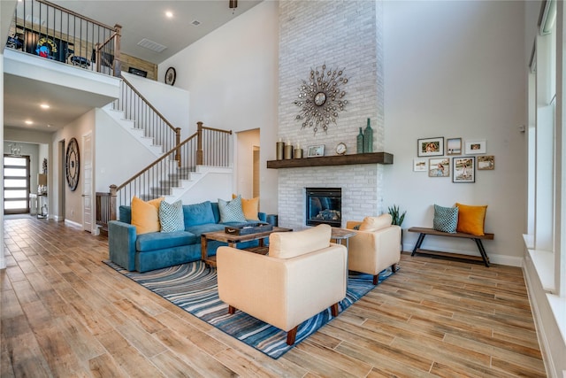 1645 Lilac Ln, Celina, TX 75009 - living room featuring a towering ceiling, stairs, wood finished floors, a brick fireplace, and baseboards