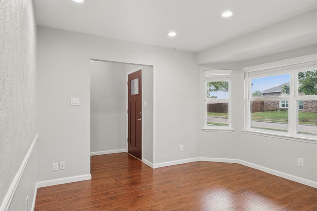 spare room featuring wood-type flooring, baseboards, a healthy amount of sunlight, and recessed lighting