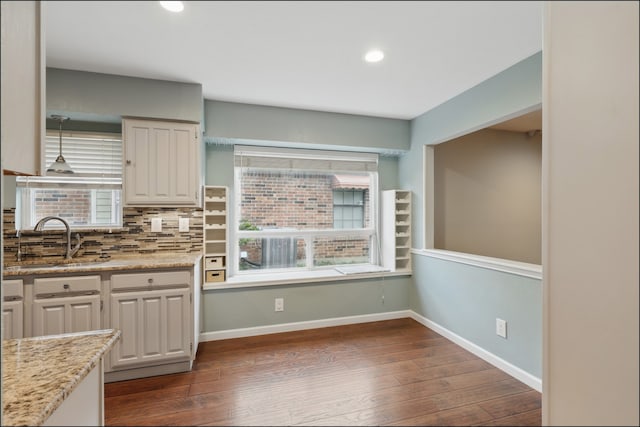 kitchen with recessed lighting, dark wood finished floors, a sink, baseboards, and tasteful backsplash