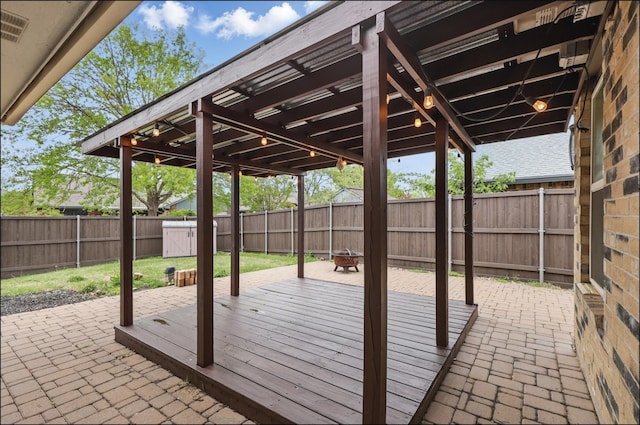 view of patio featuring a fire pit, a fenced backyard, and a deck