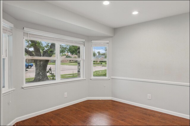spare room with recessed lighting, dark wood finished floors, plenty of natural light, and baseboards