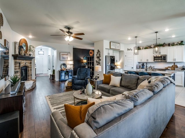 living room featuring a ceiling fan, dark wood-style floors, arched walkways, and recessed lighting