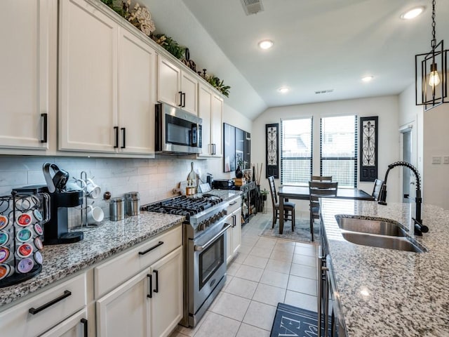 kitchen with a sink, visible vents, backsplash, decorative light fixtures, and appliances with stainless steel finishes