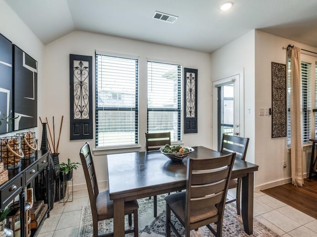 dining space featuring light tile patterned flooring, lofted ceiling, visible vents, and baseboards
