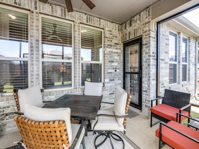 sunroom featuring a ceiling fan, a wealth of natural light, and unfinished concrete floors