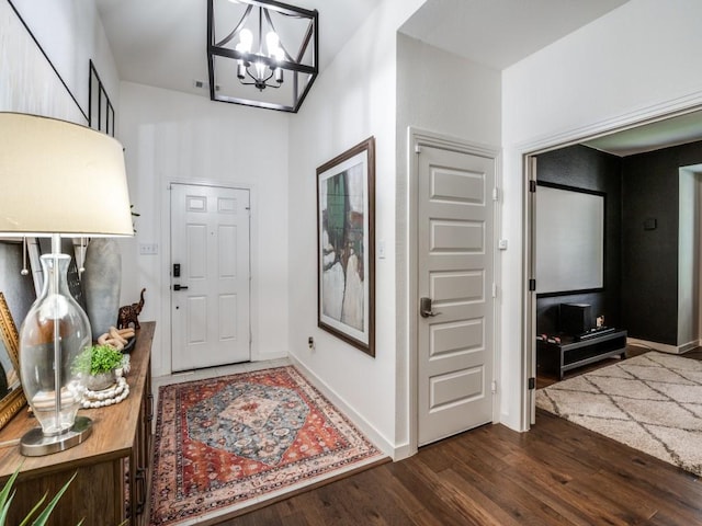 entrance foyer featuring an inviting chandelier, dark wood-type flooring, and baseboards
