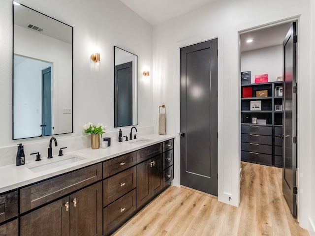 full bathroom featuring wood finished floors, a sink, double vanity, and visible vents