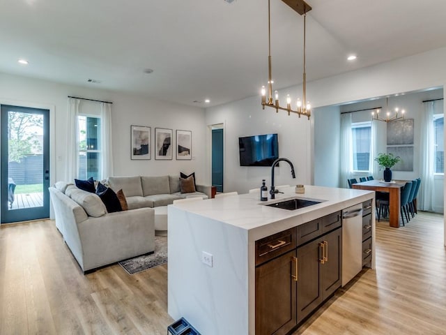 kitchen featuring open floor plan, recessed lighting, an inviting chandelier, light wood-type flooring, and a sink