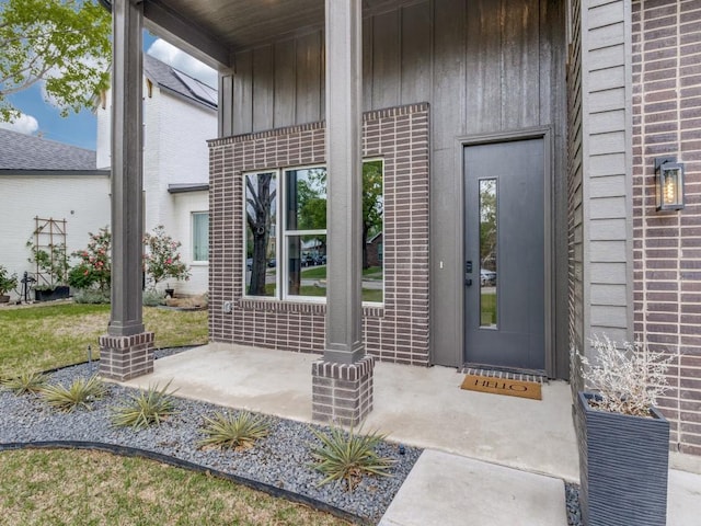 property entrance featuring board and batten siding and brick siding