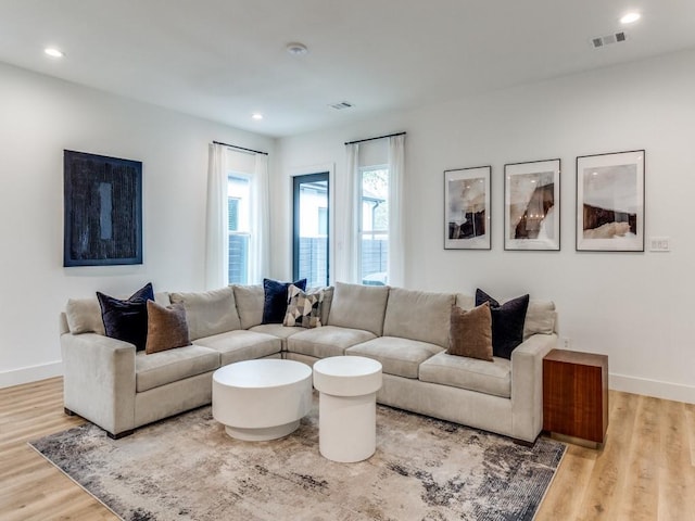 living room featuring baseboards, visible vents, and wood finished floors