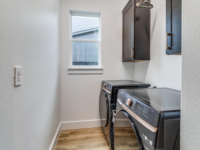 laundry area with light wood finished floors, baseboards, separate washer and dryer, and cabinet space