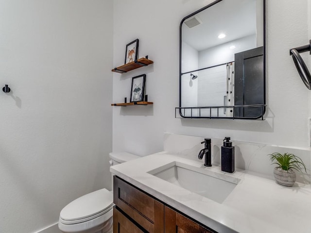 bathroom with toilet, vanity, and visible vents
