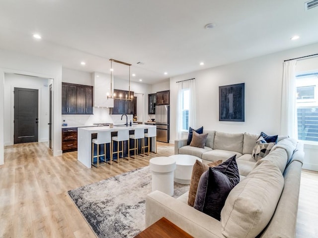 living room with light wood-style flooring, recessed lighting, a notable chandelier, and a wealth of natural light