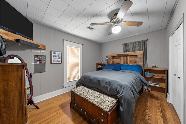 bedroom with a ceiling fan, wood finished floors, baseboards, and visible vents